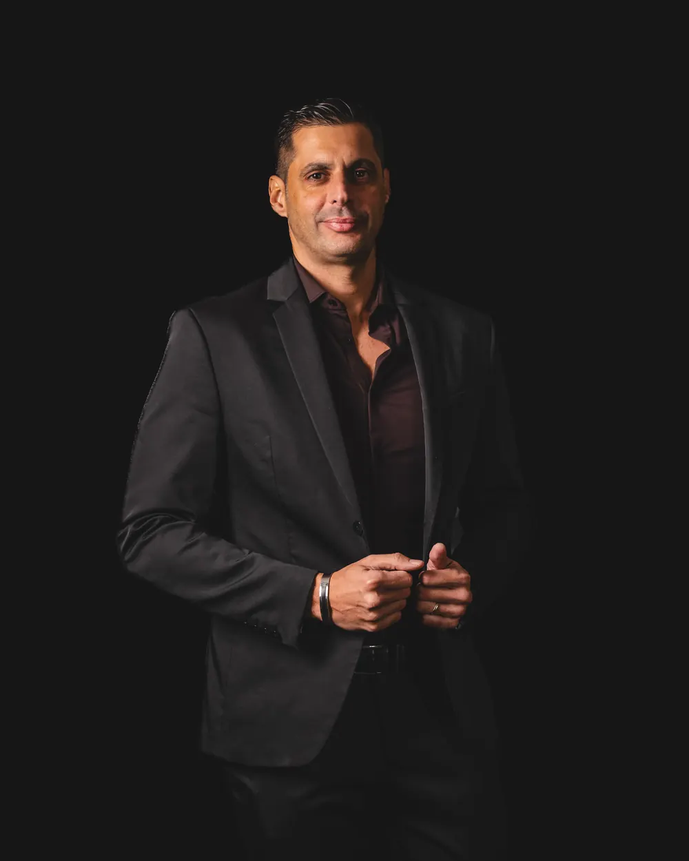 Retrato corporativo de Carlos Jimenez con traje oscuro sobre fondo negro