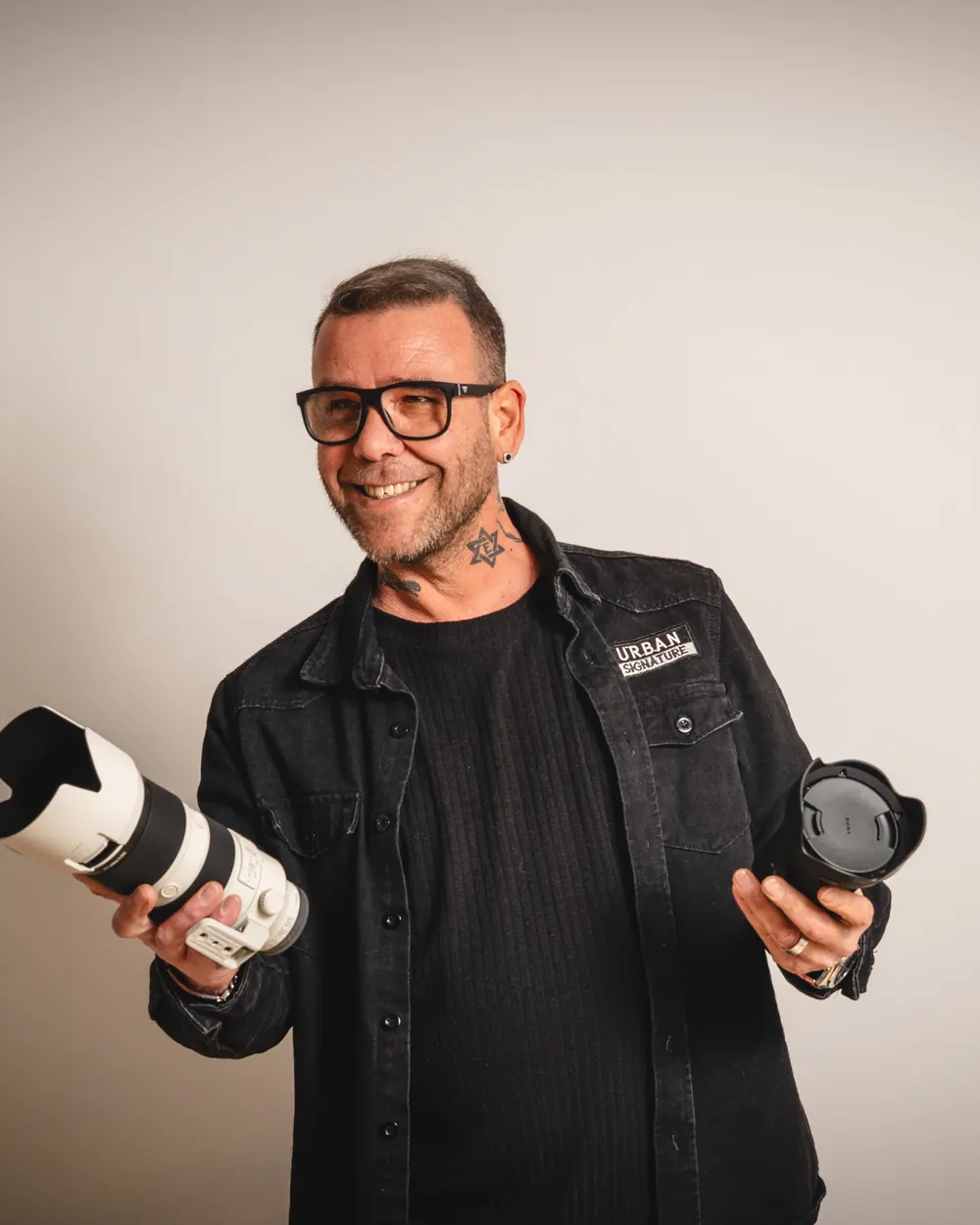 Jose Richarte, fotógrafo en Mallorca, sonriendo con dos objetivos en las manos