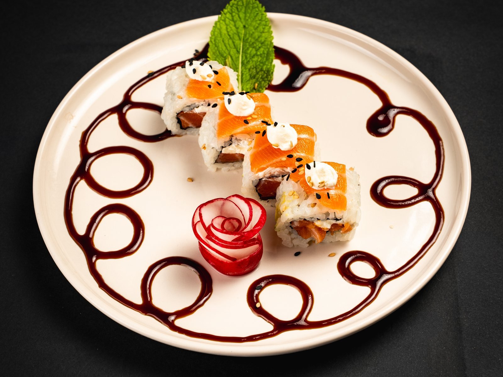 Sushi en plato blanco con decoración de salsa, plato protagonista en las fotos para la carta