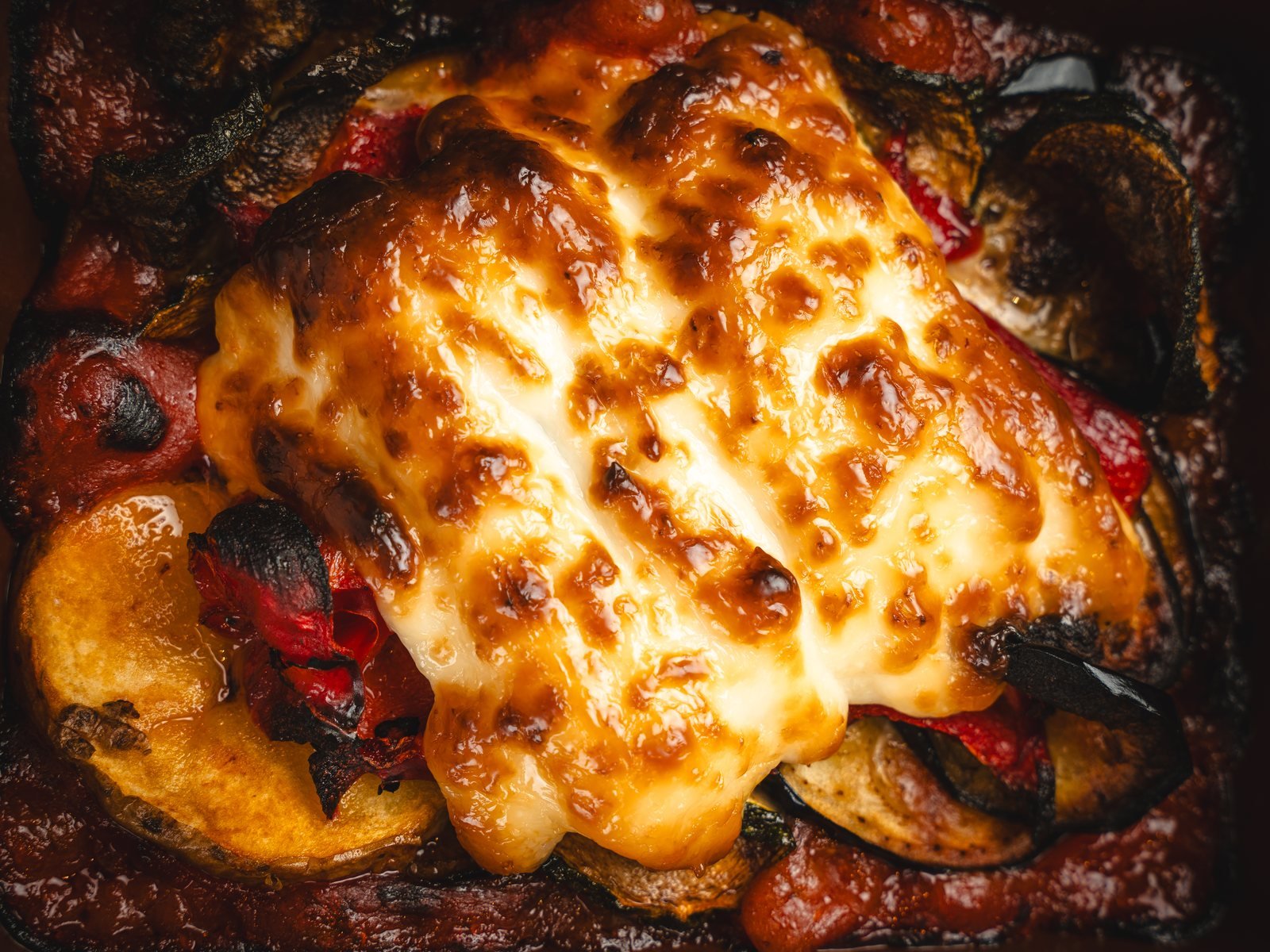 Verduras gratinadas con queso fundido de cerca, textura en fotos para la carta de restaurante