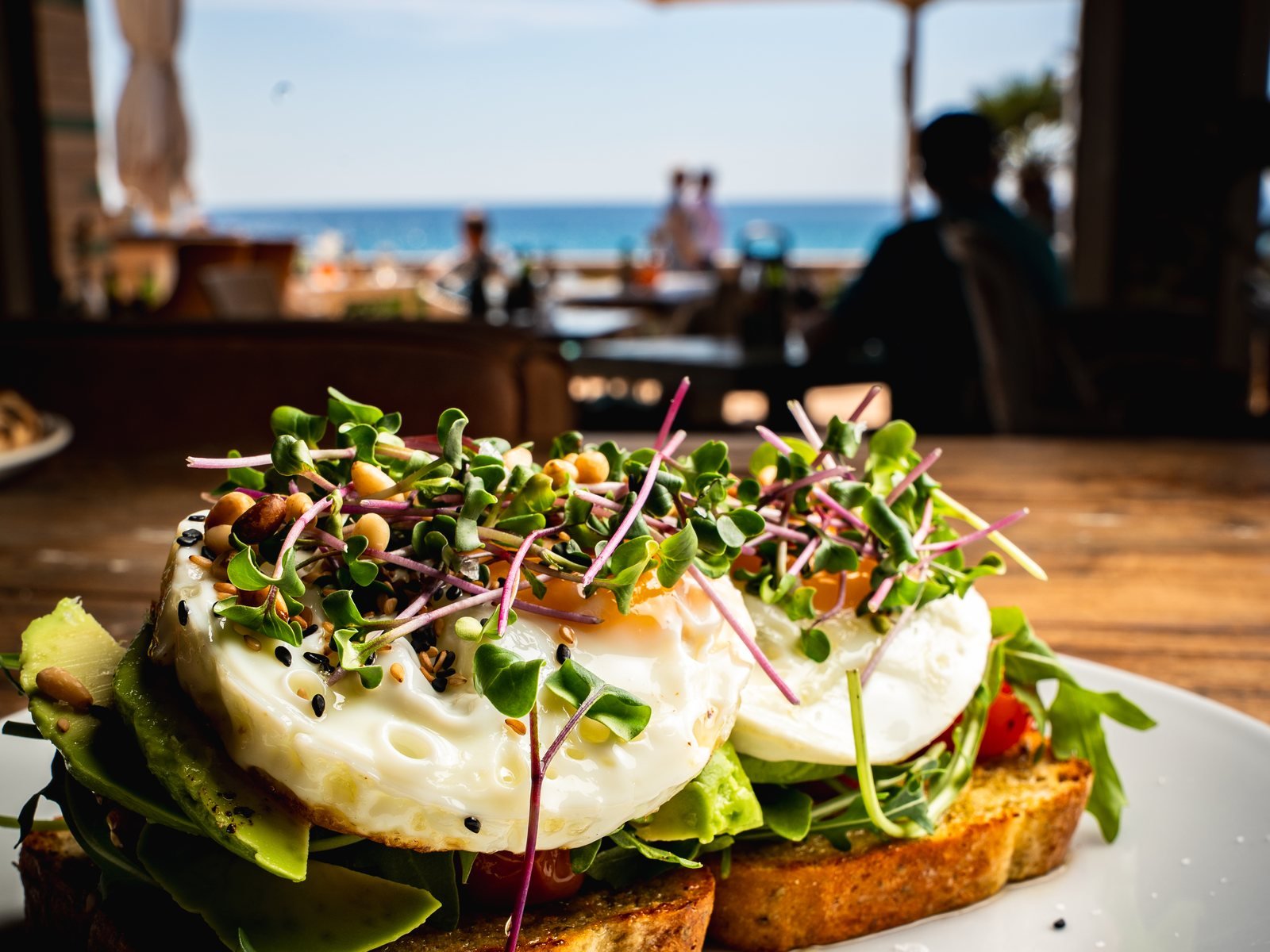 Tosta con huevos y brotes en una terraza con vistas al mar en Mallorca