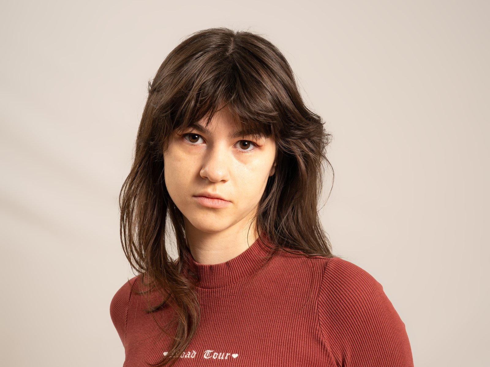 Retrato de estudio de una chica con jersey de punto liso color teja sobre fondo claro