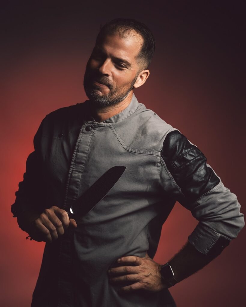 Retrato de chef con cuchillo y mano en la cadera sobre fondo rojo, estudio de Cala Ratjada